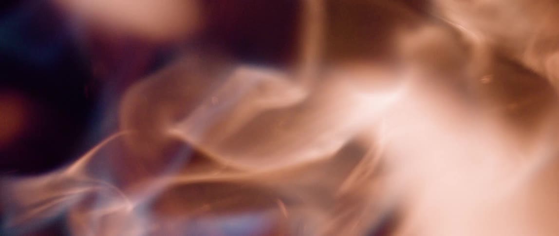 White smoke with blue and red hues against black background