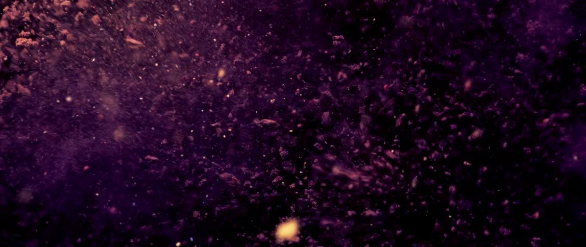 A dense cloud of purple particles is suspended in the air floating and swirling against a dark background