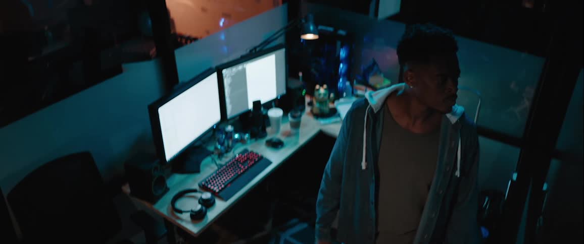 Man inside a room with computer setup looking to the side intently