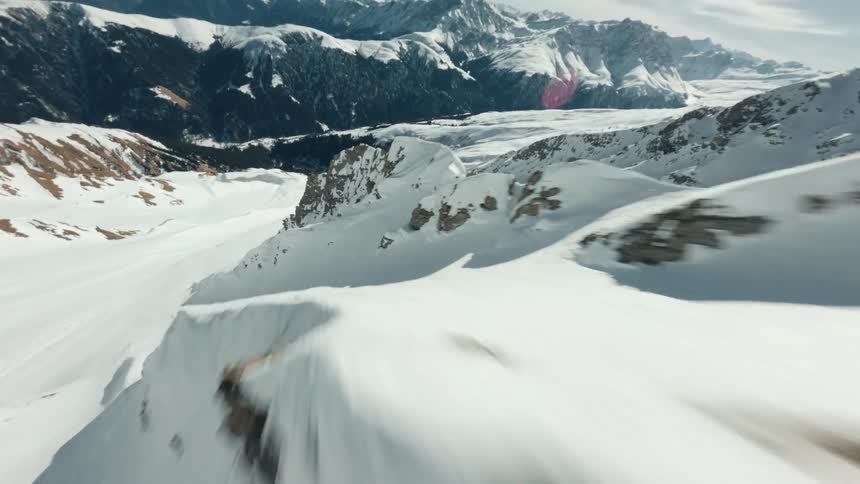 FPV Drone Flying Down a Snow-Covered Mountain Ridge in Breathtaking Descent