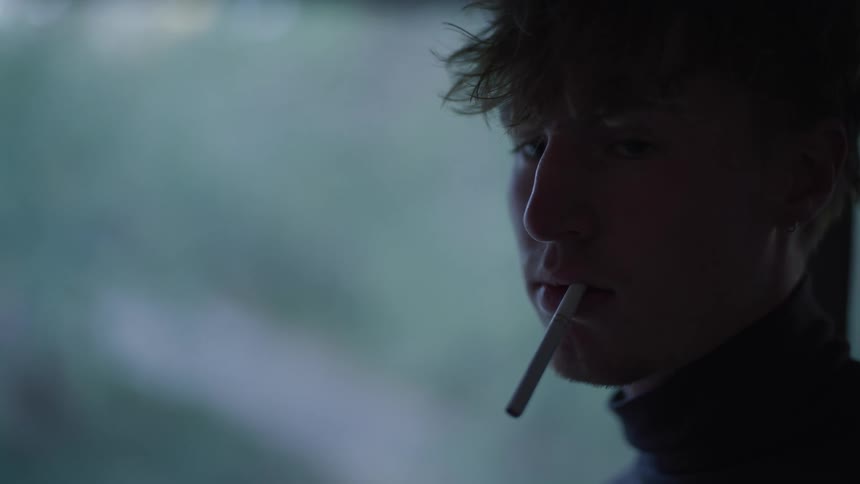 The face of a young man with an unlit cigarette in his mouth