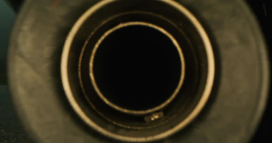 Golden muffler hangs near the wheel of a vehicle standing on a road