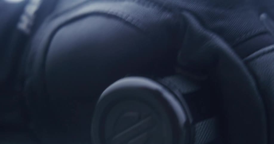 A gloved hand grips the handlebar tightly as the biker rides the motorcycle fast with the sleek metallic throttle reflecting the motion