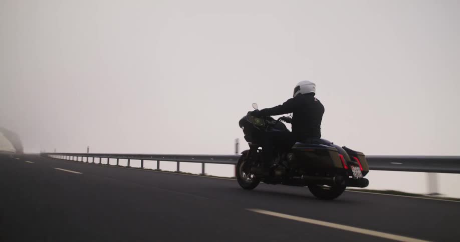 A man is driving his motorcycle through the fog