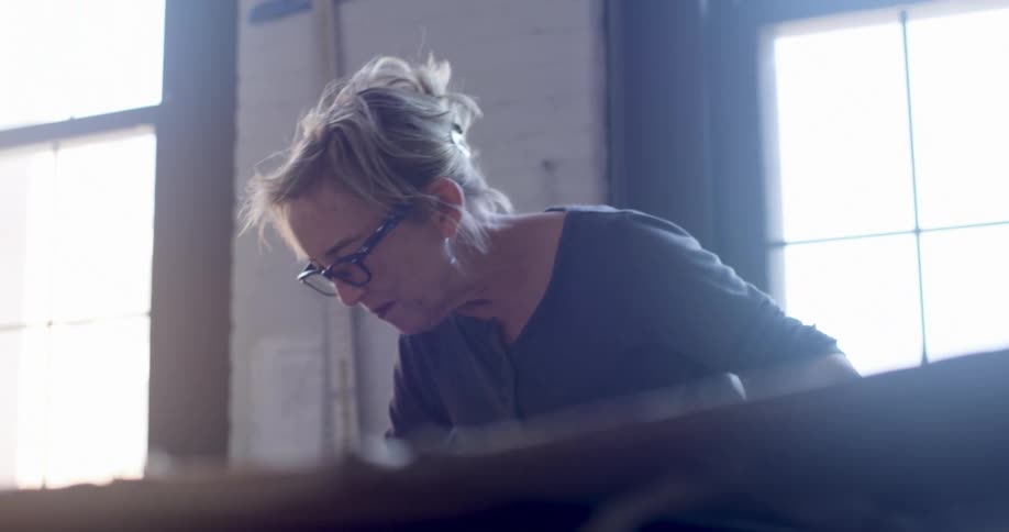 A woman is talking and smiling while working in a manufacturing shop