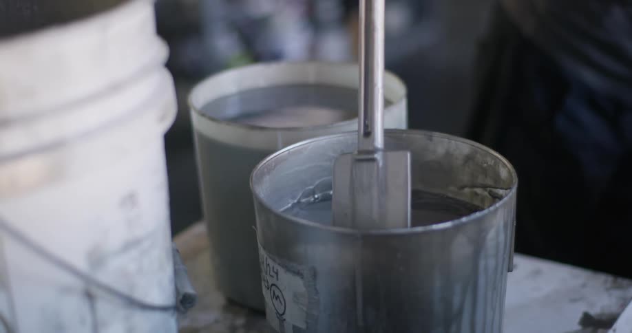 A person is mixing silver paint in the workshop