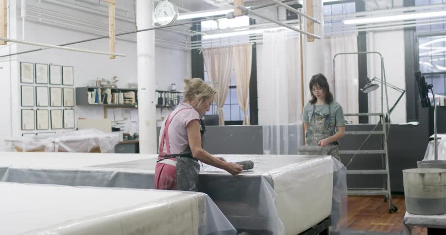 Two workers are using rollers on the plastic sheets