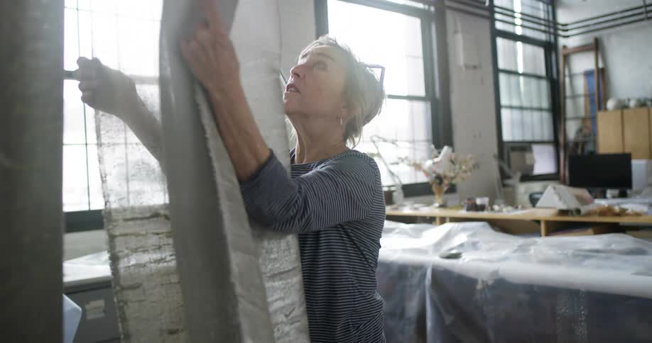 The tailor walks over and feels a roll of fabric