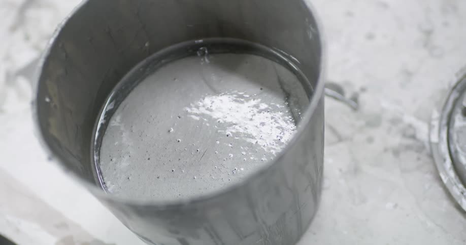 A metal cup is filled with white liquid
