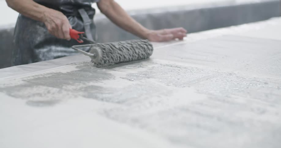 A person is using a paint roller to paint wood