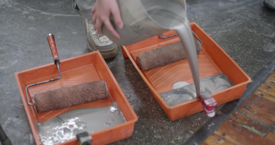 Person pours gray paint into orange trays
