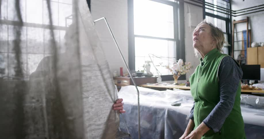 Two women look closely at a large piece of translucent fabric