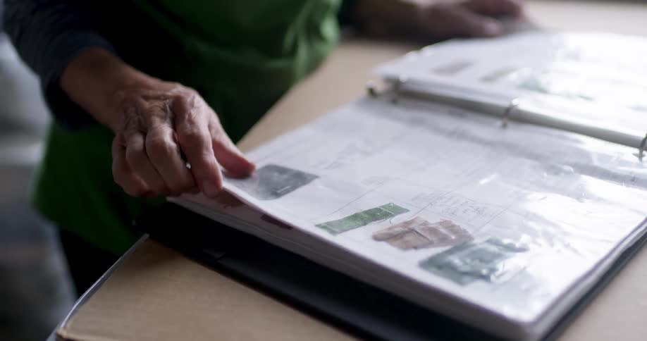 A person is standing looking through a book at a table