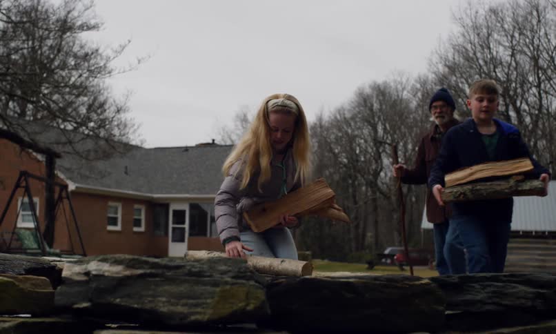 Grandfather accompanying his two grandchildren carrying firewood in a backyard