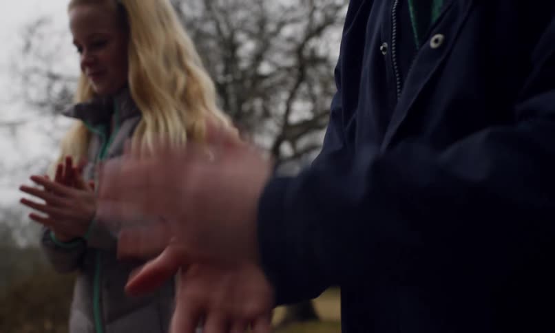Two children wearing thick jackets in the countryside are dusting off their hands by clapping them