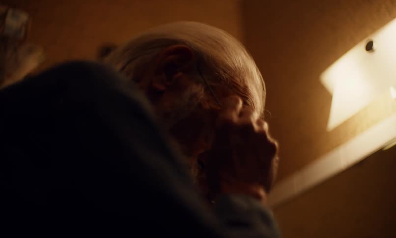 Elderly man taking off and putting on his glasses while shaving in front of the mirror