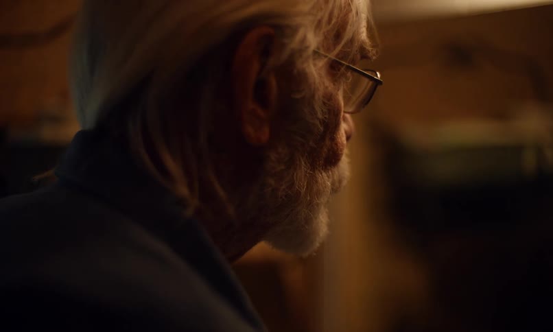 Elderly man looks at himself in a mirror before putting on his eyeglasses