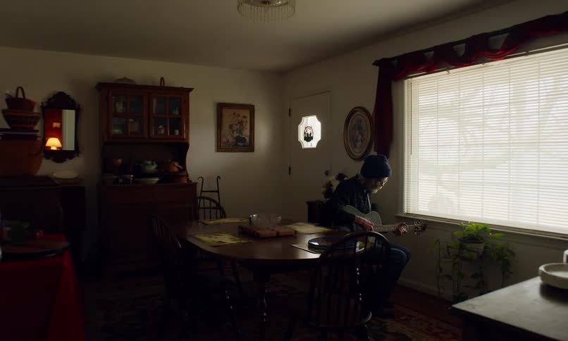 Elderly man sitting in living room playing guitar