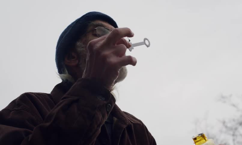Elderly man standing outdoors blows bubbles during the daytime
