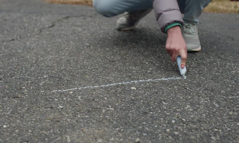Girls hands picking up a crayon and drawing on the floor