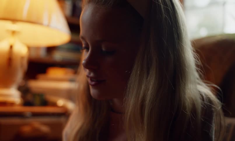 A girl smiles as she moves forward in her seat and reaches for something