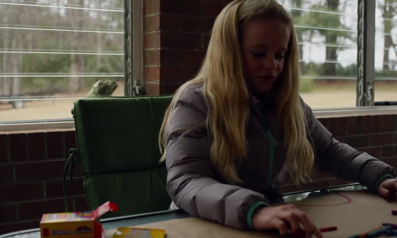 Kids are at a table coloring with pencils and crayons on a large sheet of paper