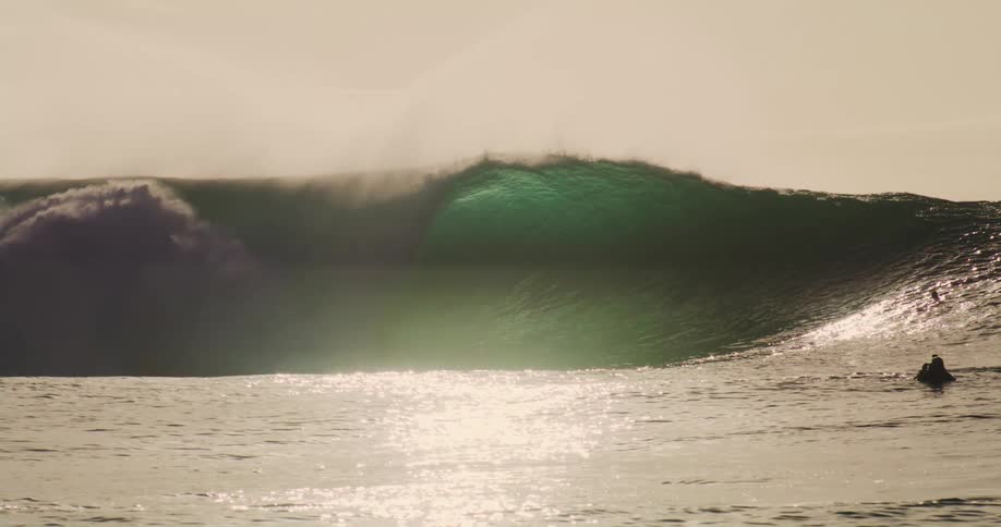 Two people from inside the ocean watching a tubular wave