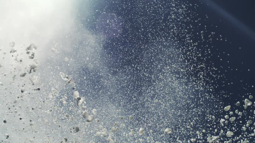 Explosion of water droplets captured in motion against the sky