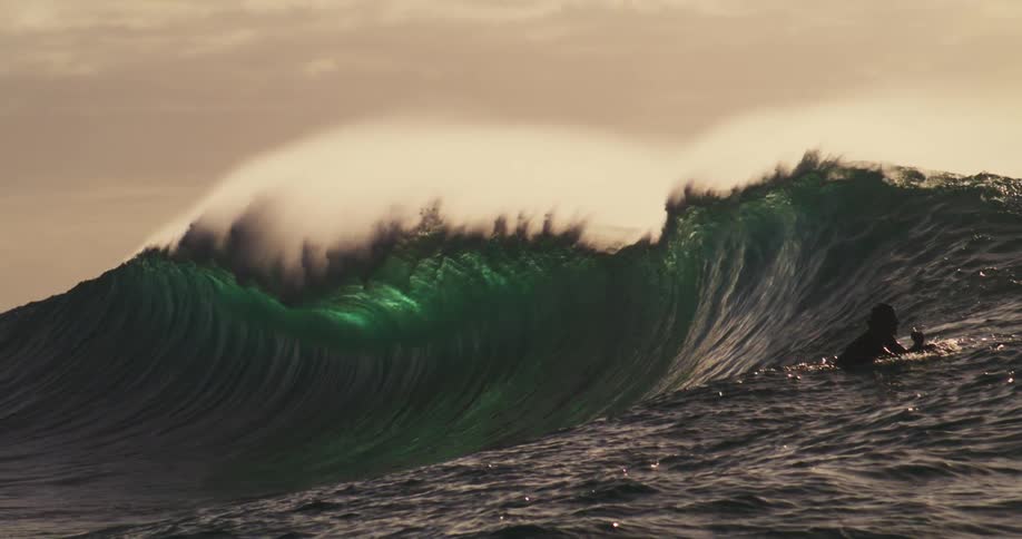 Surfers move as a large wave approaches