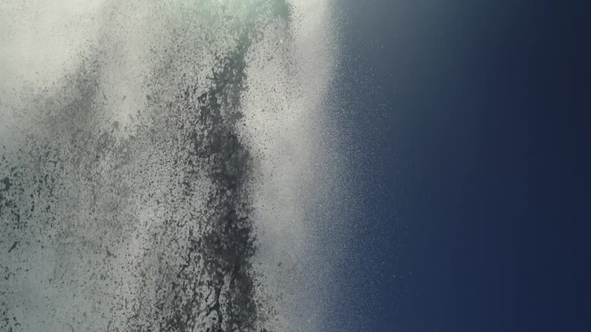 Water jet with foam rising against a blue sky
