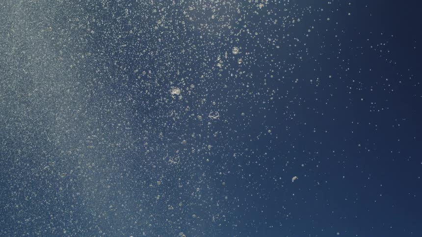 Water particles suspended in the air illuminated by the sun against a deep blue sky
