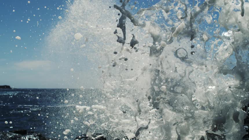 Waves crashing onto the shore and causing the water to rise with foam