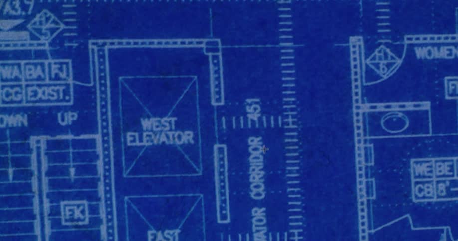 Close up of a blueprint detailing plans for an office building with multiple offices, corridors, and elevators.