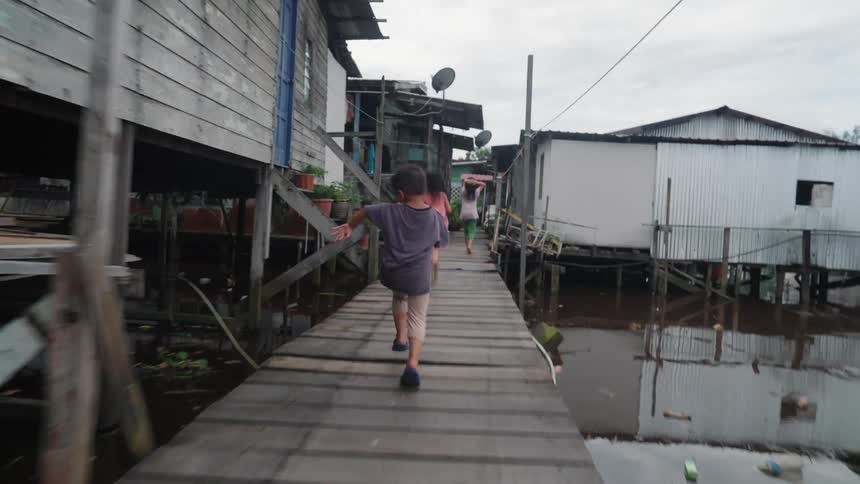 Children running in a poor community on the banks of a polluted river