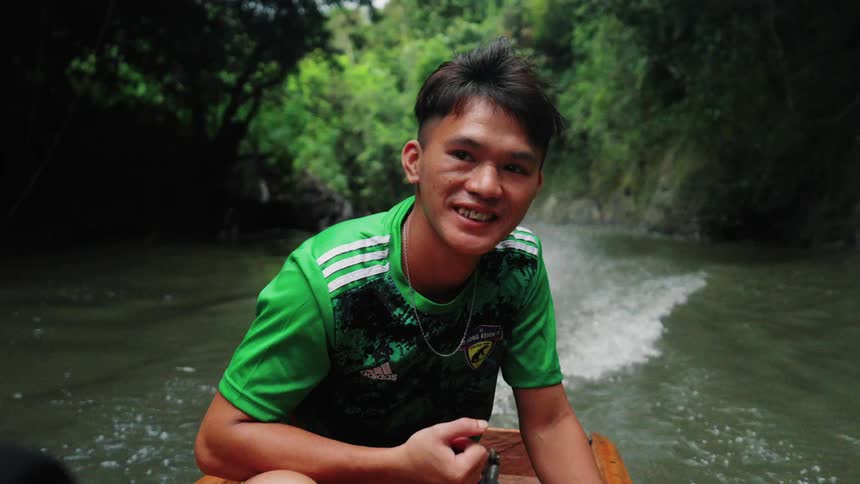 Portrait of a smiling man while standing in a boat moving down a river