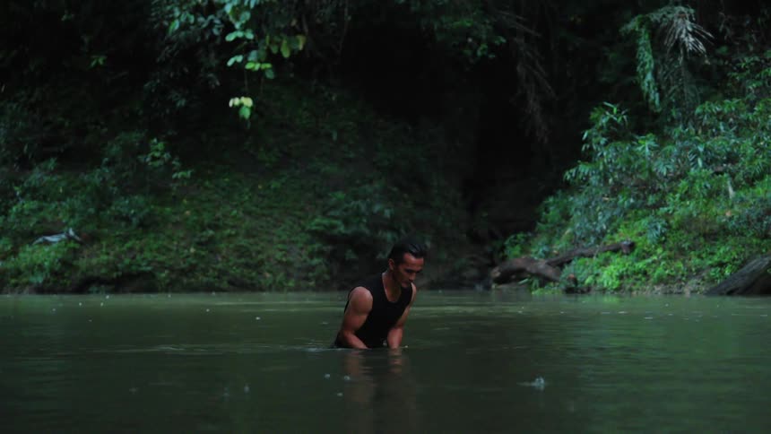Man diving into a river holding a rock