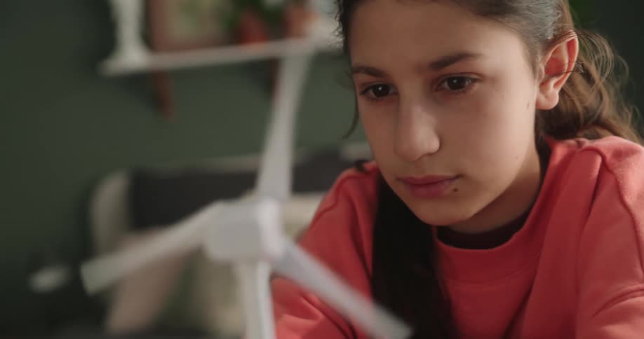 Girl sitting interacting with a small wind power model