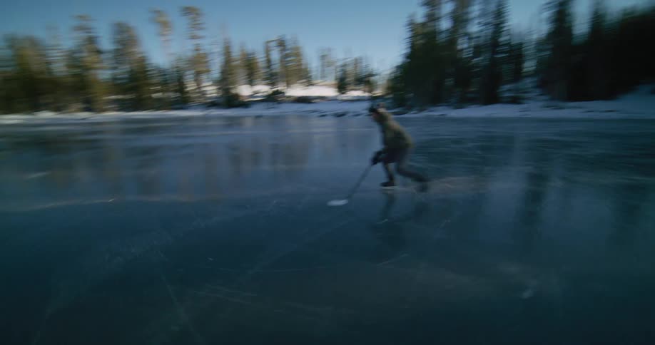 A man ice skates on a frozen river in a forest