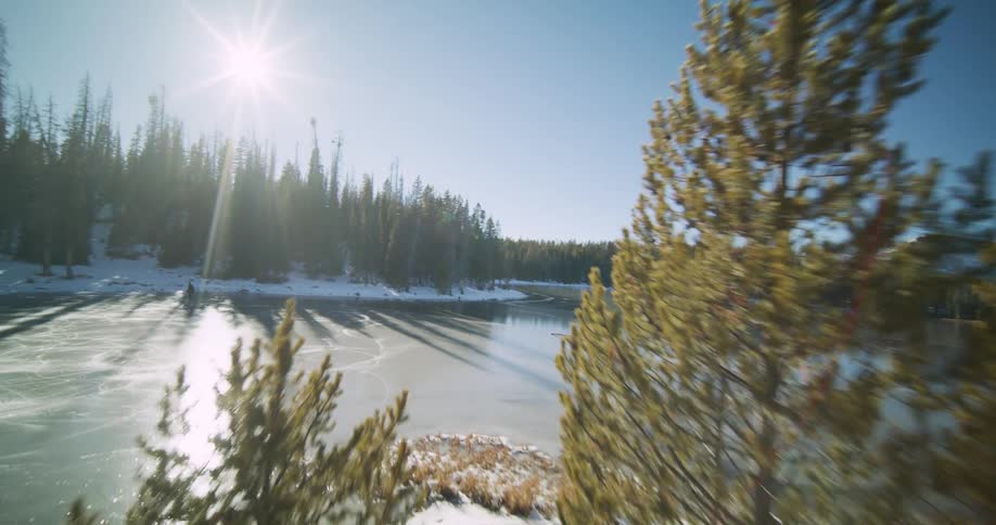 A river comes into view through snowy terrain filled with trees