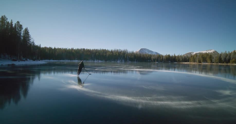 A man is leaving figure eight marks on the ice of a frozen lake