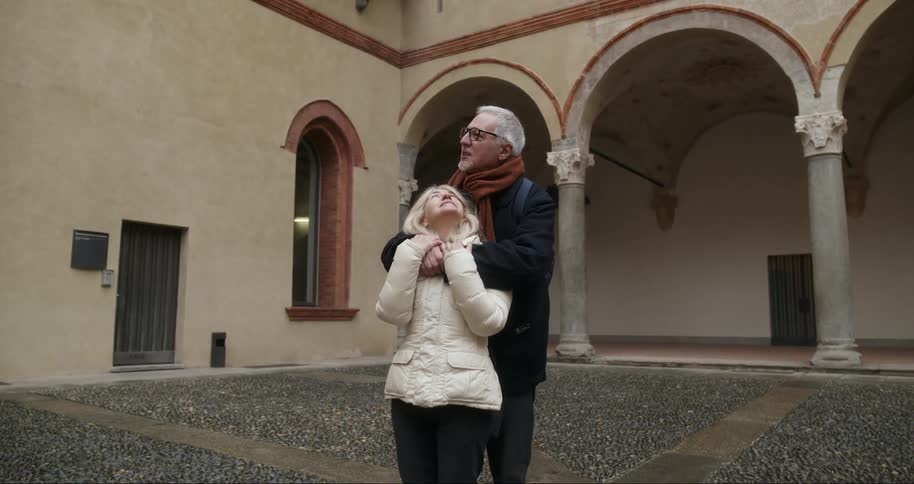 A couple of tourists are hugging outside of the building