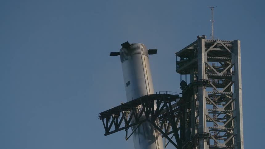 SpaceX Starship rocket booster making a vertical landing inserts itself in a launchpad structure during the day