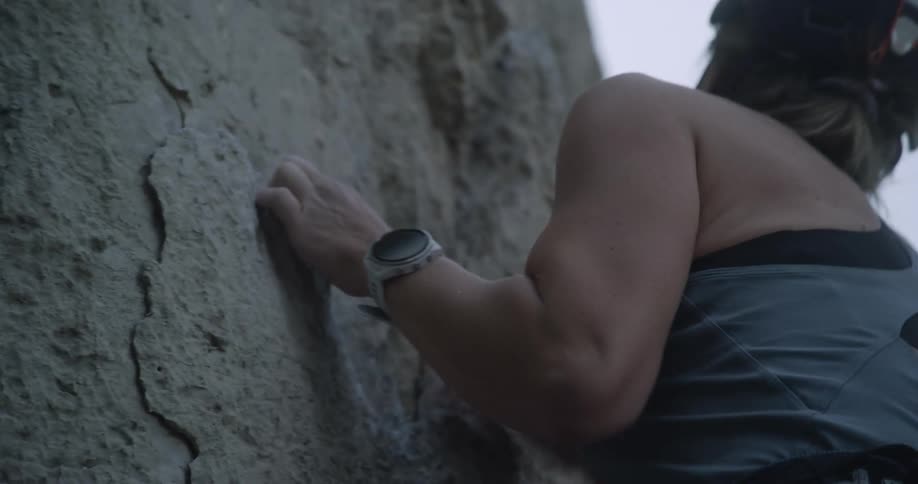 A woman is rock climbing on a cloudy day
