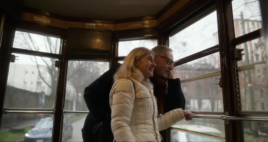 A couple are traveling by trolley as cars pass by