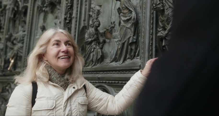 A woman smiles as she touches the carvings on the wall