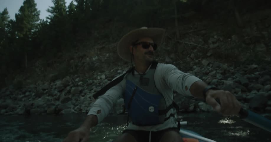 Happy man in sunglasses and hat driving a rowing boat