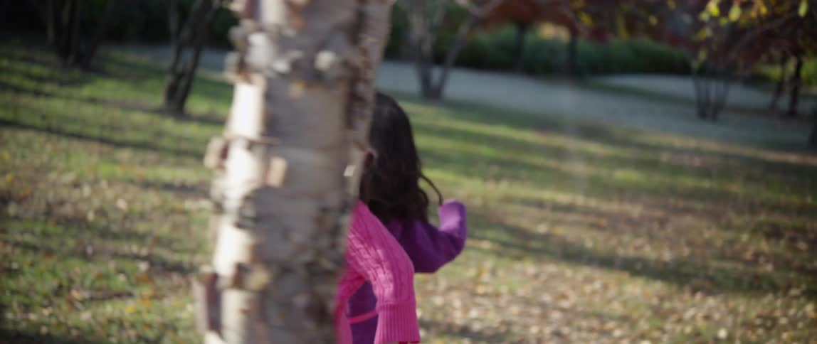 Two girls run through a park