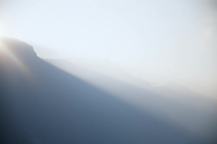 Silhouette of a mountain with fog and the solar reflection of dawn