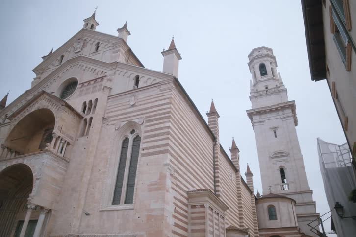 Facade of a classical church with a large tower in the background