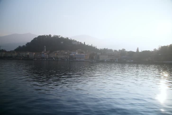 A coastal city facing a large body of water with a surface reflecting sunlight